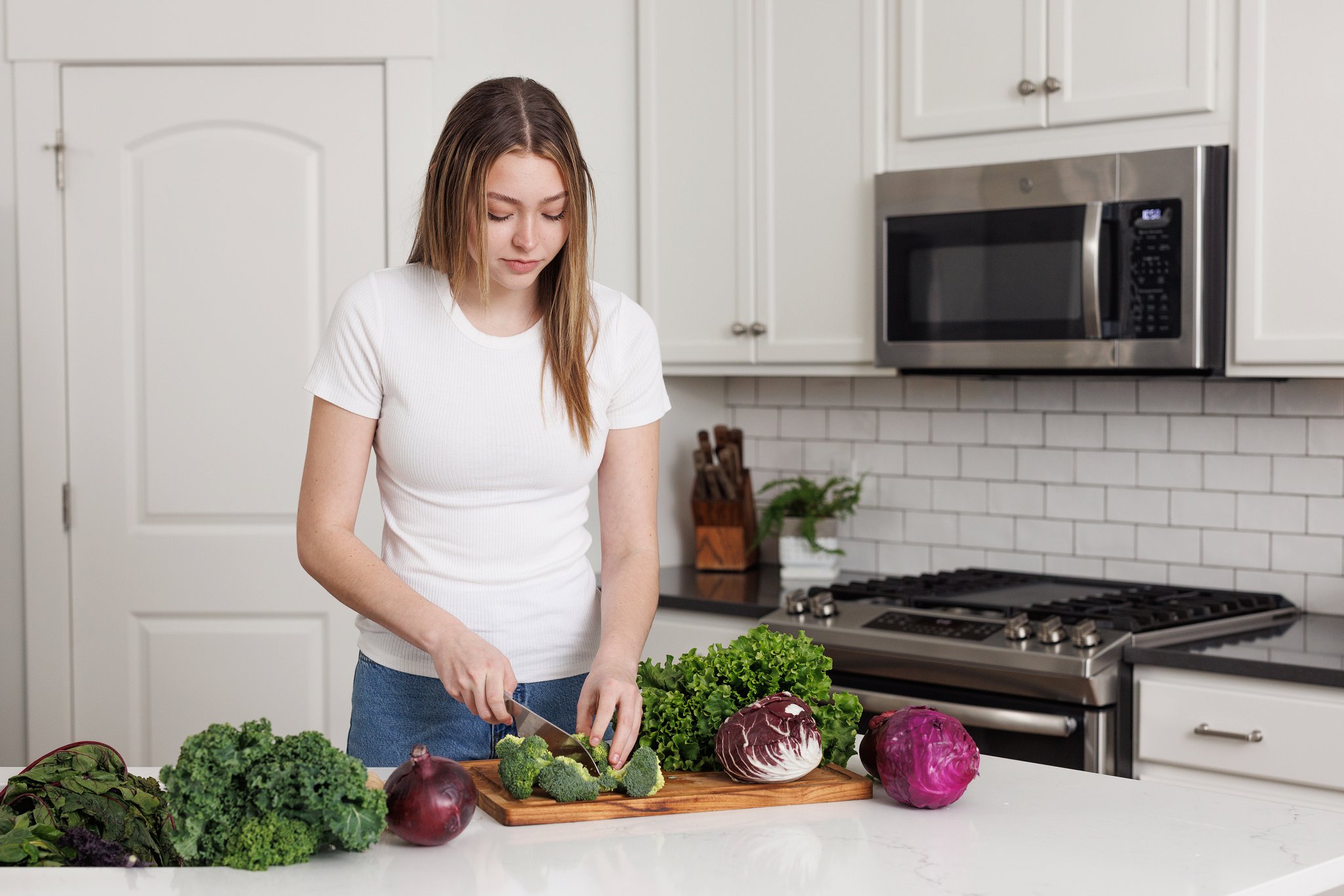 woman standing in kitchen, smiling, looking off camera, cooking from root meal plan